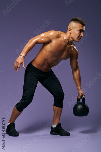 muscular handsome man lifting weight, preparing for a contest. challenge. full length side view photo. isolated blue background, studio shot. healthy lifestyle