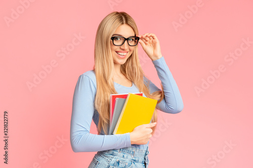 Teenager in specs holding notebooks at studio