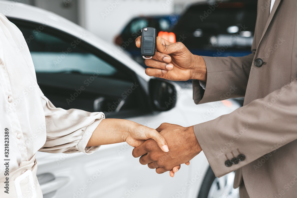 Seller Greeting Lady With Handshake Giving Car Key In Dealership Seller Greeting Lady With Handshake Giving Car Key In Dealership