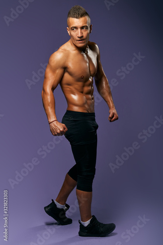 slim sexy guy with ideal body performing oon the studio Workout bodybuilding concept.isolated blue bckground, studio shot,