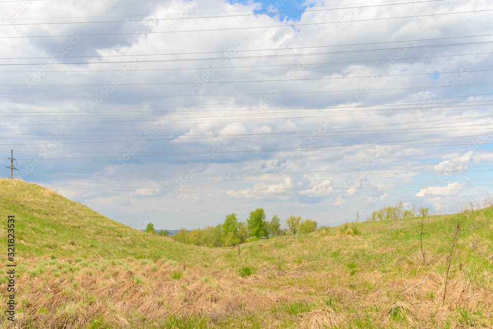 Landscape with grass in a ravine and power lines against the sky