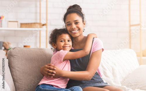 Happy african american sisters embracing at home