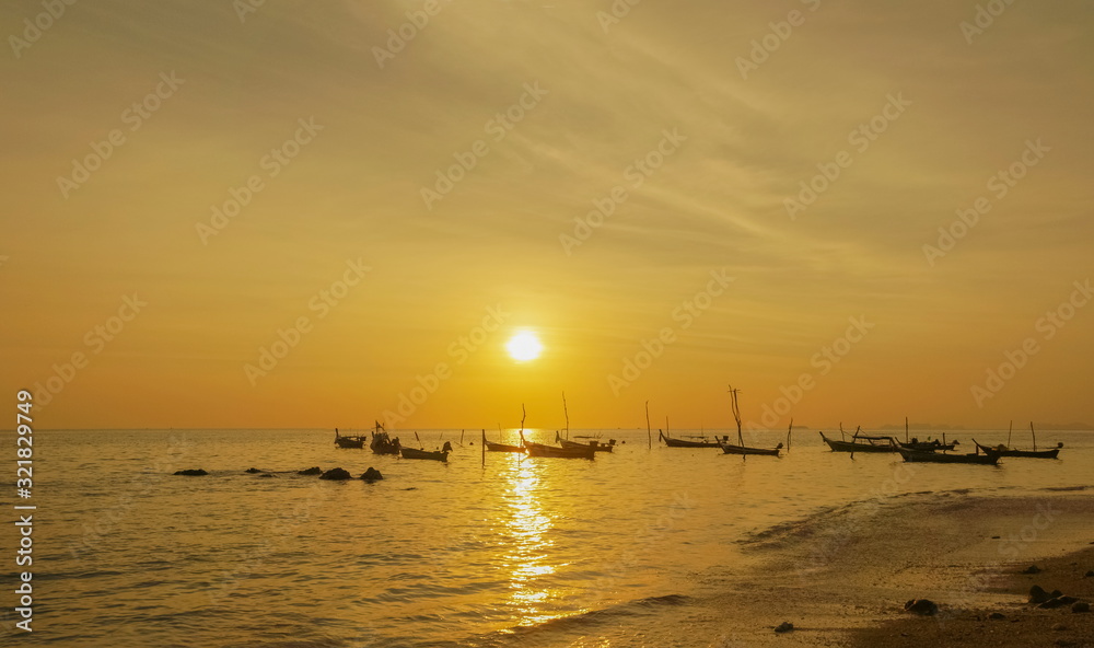 view seaside evening of many fishing boats floating in the sea with yellow sun light in the sky background, sunset at Klong Hin Beach, Ko Lanta island, Krabi, southern of Thailand.