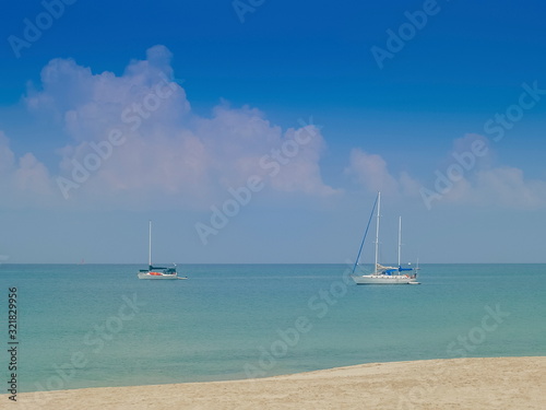 view of white Yacht floating in blue-green sea with cloudy and blue skybackground, Ba Kan Tiang Bay, Ko Lanta island, Krabi, southern of Thailand.