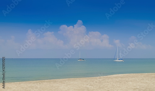 view of white Yacht floating in blue-green sea with cloudy and blue skybackground, Ba Kan Tiang Bay, Ko Lanta island, Krabi, southern of Thailand.