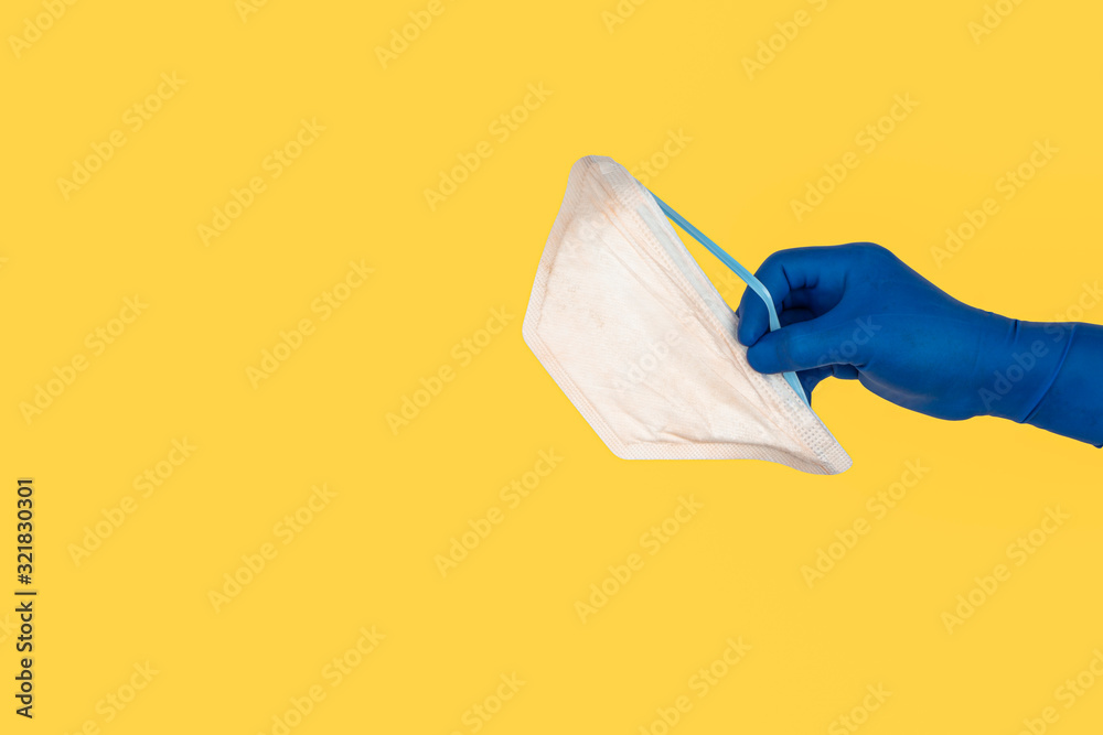 Hands holding protection medical mask on yellow background. Healthcare and copy space concept Hands holding protection medical mask on yellow background. Healthcare and copy space concept