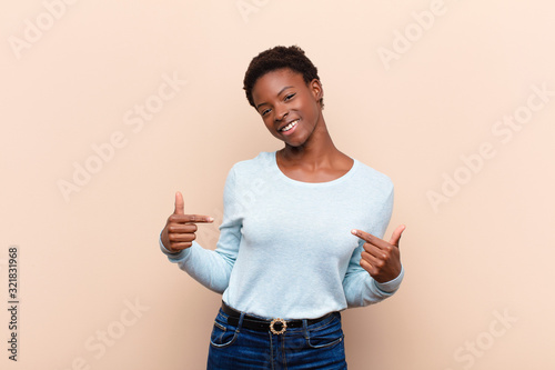 young pretty black womanlooking proud, arrogant, happy, surprised and satisfied, pointing to self, feeling like a winner photo