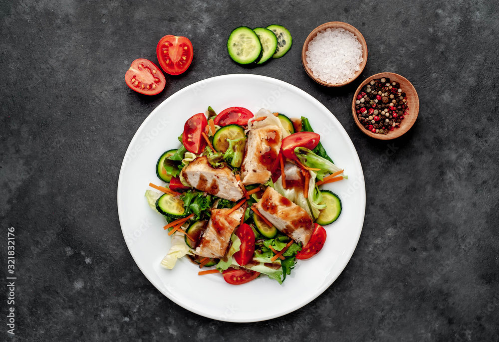 a plate of salad of tomato, chicken, cucumber, carrots, soy sauce in a plate on a stone background a plate of salad of tomato, chicken, cucumber, carrots, soy sauce in a plate on a stone background
