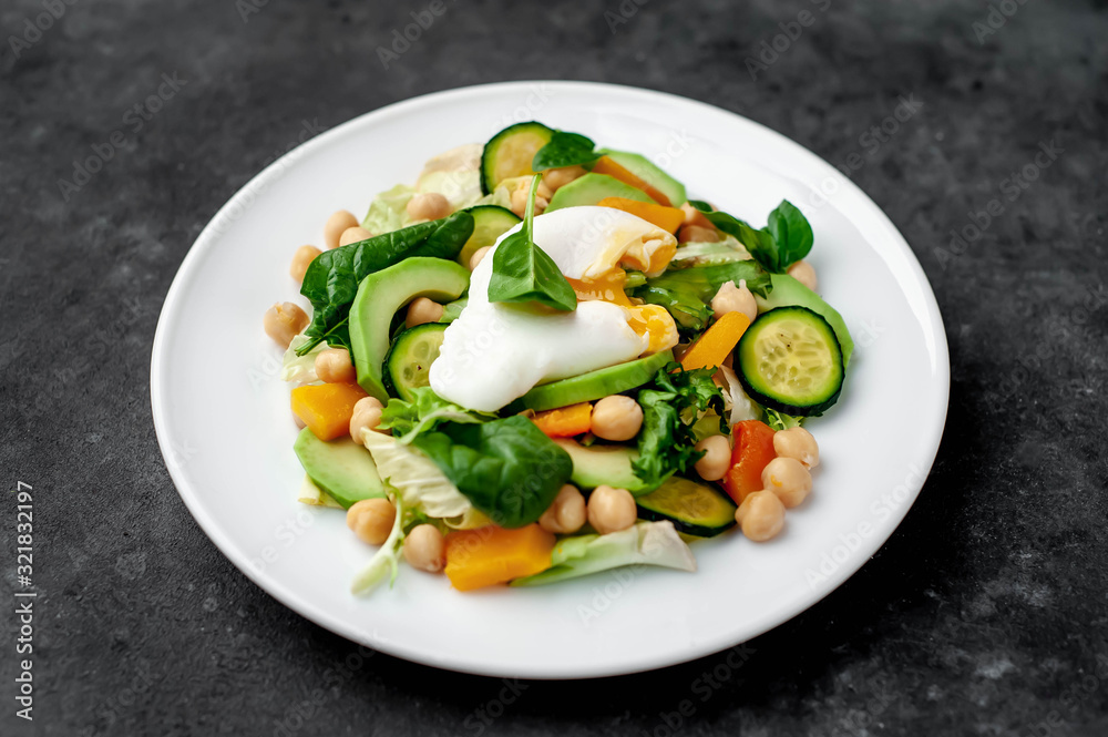 a plate of avocado salad, chickpeas, pumpkin, cucumber, poached egg in a plate on a stone background a plate of avocado salad, chickpeas, pumpkin, cucumber, poached egg in a plate on a stone background
