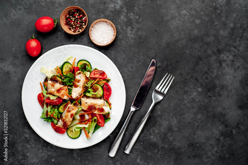 plate of tomato, chicken, cucumber, carrot, soy sauce salad in a plate on a stone background with copy space for your text