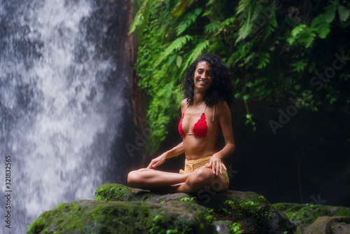 outdoors tropical lifestyle portrait of young attractive and happy hipster girl enjoying nature excited feeling free at amazing beautiful waterfall in exotic holidays travel