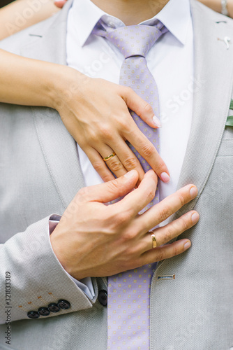 Hands of the bride and groom with wedding rings. The groom holds the bride's hand