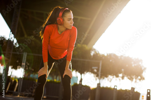 Attractive female runner taking break after jogging outdoors