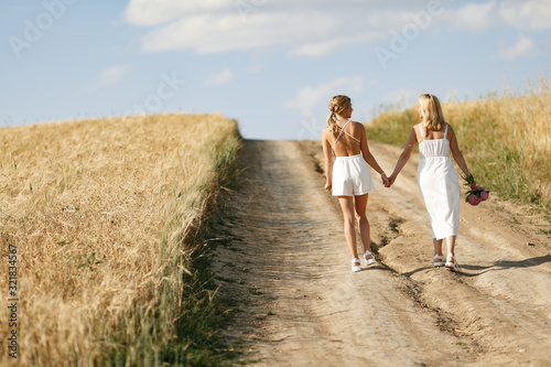 Adult mother with daughter. Beautiful girl in a white dress. Family in a summer field © prostooleh