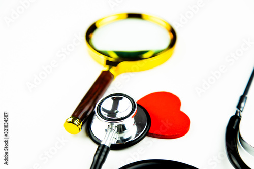 Stetoskop, serce i lupa lekarska na białym tle