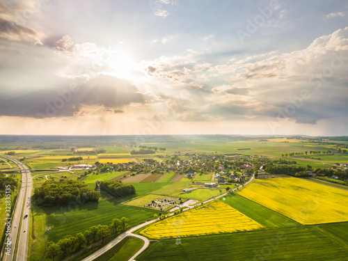 Yellow and green rapeseed fields next to the highway on the aerial shot