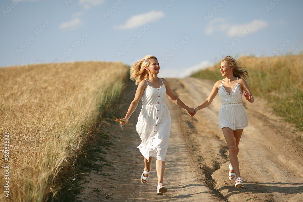 Adult mother with daughter. Beautiful girl in a white dress. Family in a summer field Adult mother with daughter. Beautiful girl in a white dress. Family in a summer field