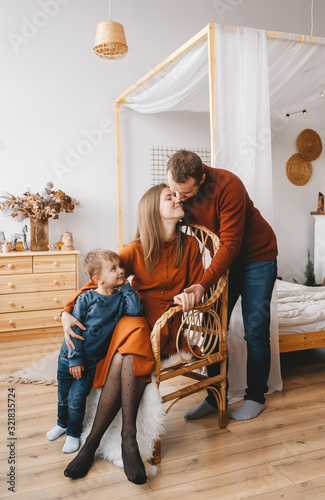 Couple kissing while their baby standing near them and looks on them.