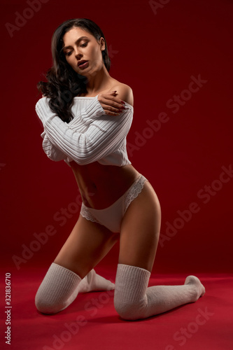 Female model in sweater posing on knees.