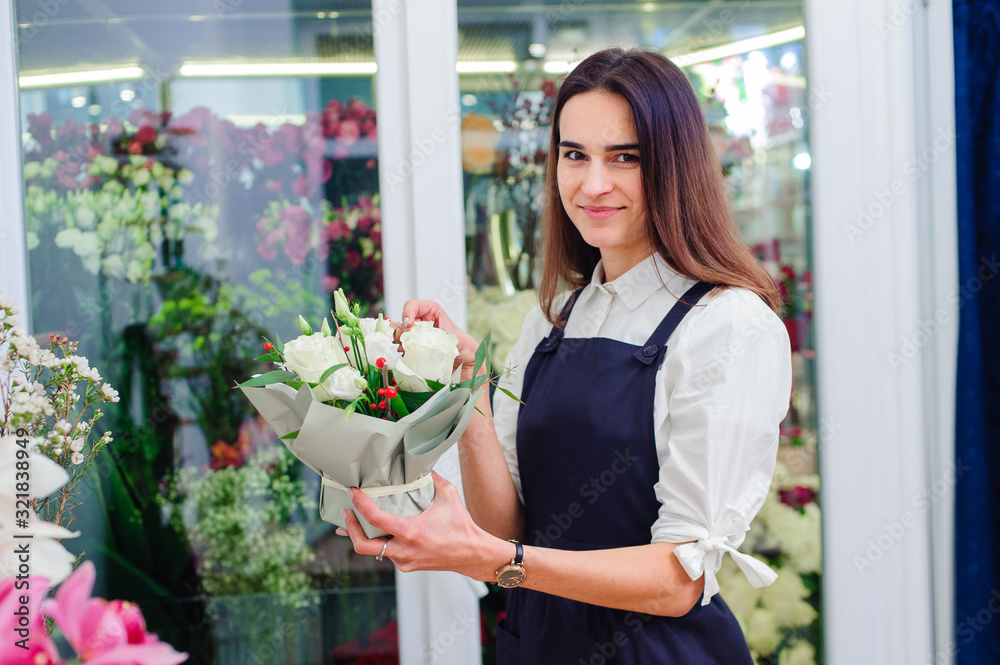 The owner of a flower shop makes a bouquet with white roses The owner of a flower shop makes a bouquet with white roses
