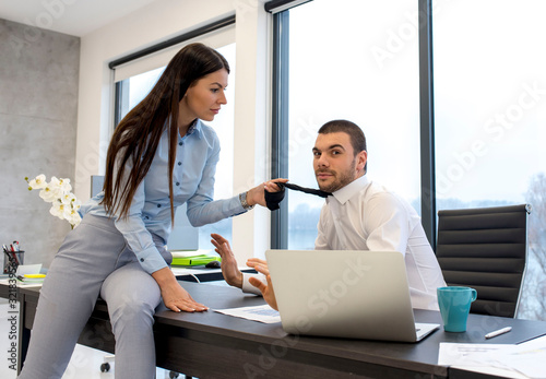 Obraz na plátně Attractive businesswoman draws colleague for his tie in the office