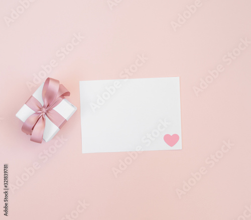 Valentine's day mockup. Greeting card with a gift and white paper on a pastel pink background. Valentine's day concept. © miss.lemon
