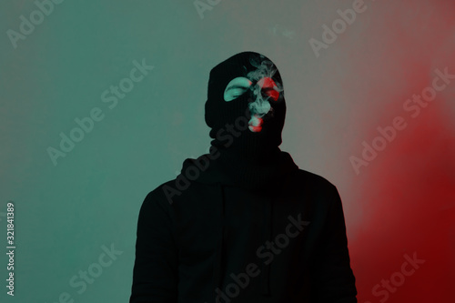 Cuadro en lienzo young man in hoodie and balaclava closing eyes and blowing smoke out