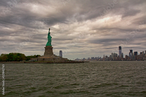 Freiheitsstatue mit Blick auf New York Skyline, bewölkter Himmel 