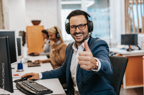 Foto Handsome male customer service agent working in call center office as a telemarketer