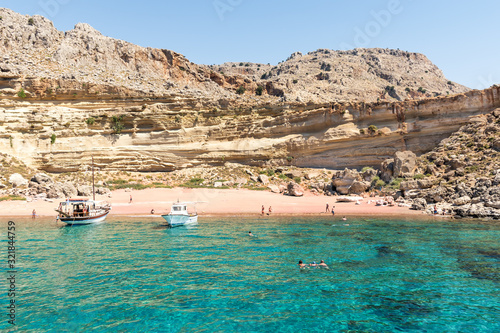 Fototapeta Naklejka Na Ścianę i Meble -  Tourist boats anchored by Red Sand beach, people have fun (Rhodes, Greece)