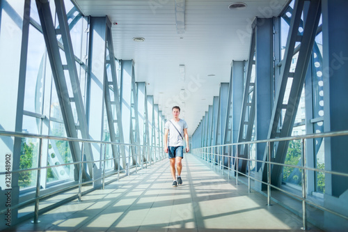 Front view of handsome gentleman strolling over big bridge. Good-looking guy wearing t-shirt and denim shorts while taking walk. Concept of man in city. © YouraPechkin