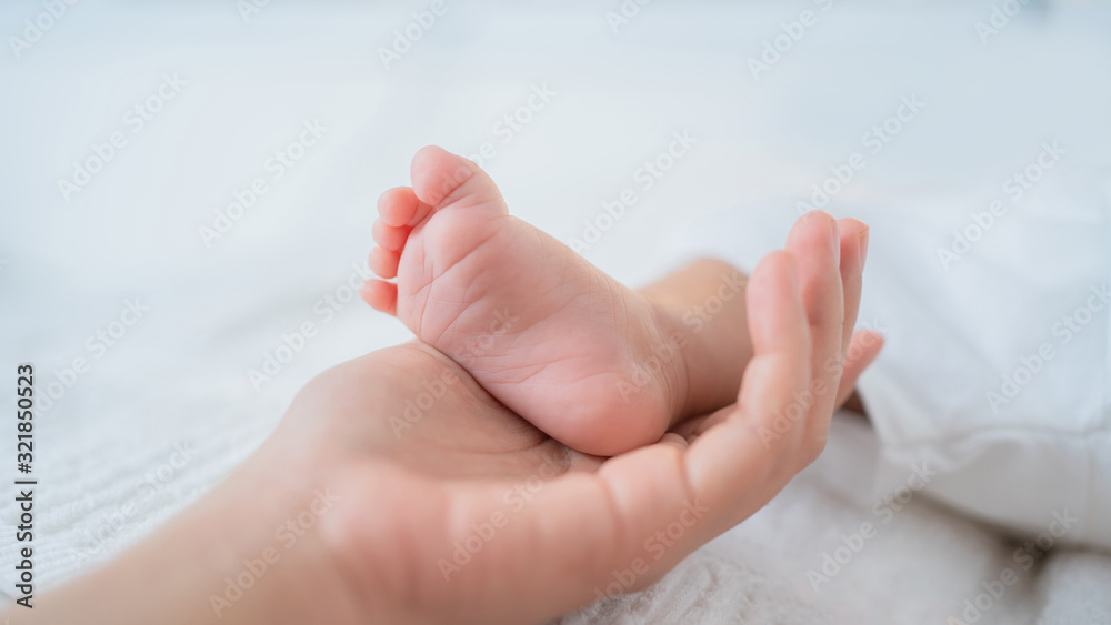 The mother's hand touches the baby's foot. The mother's hand touches the baby's foot.