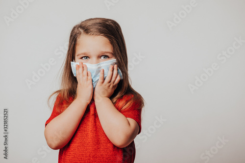 Masked child - protection against influenza virus. Little Caucasian girl wearing mask for protect pm2.5. Biological weapons. baby on a gray background with copy space. epidemic, pandemic. 