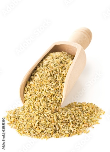 Heap of uncooked, raw freekeh or firik, roasted wheat grain, in wooden scoop over white photo