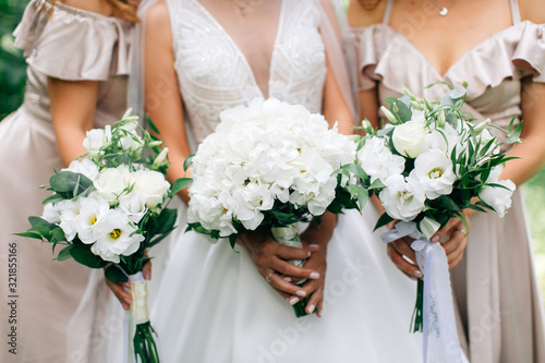 Bride and bridesmaids holding beautiful bouquetes photo