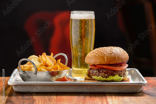 Fast food. A big burger with beef and a glass of beer. 