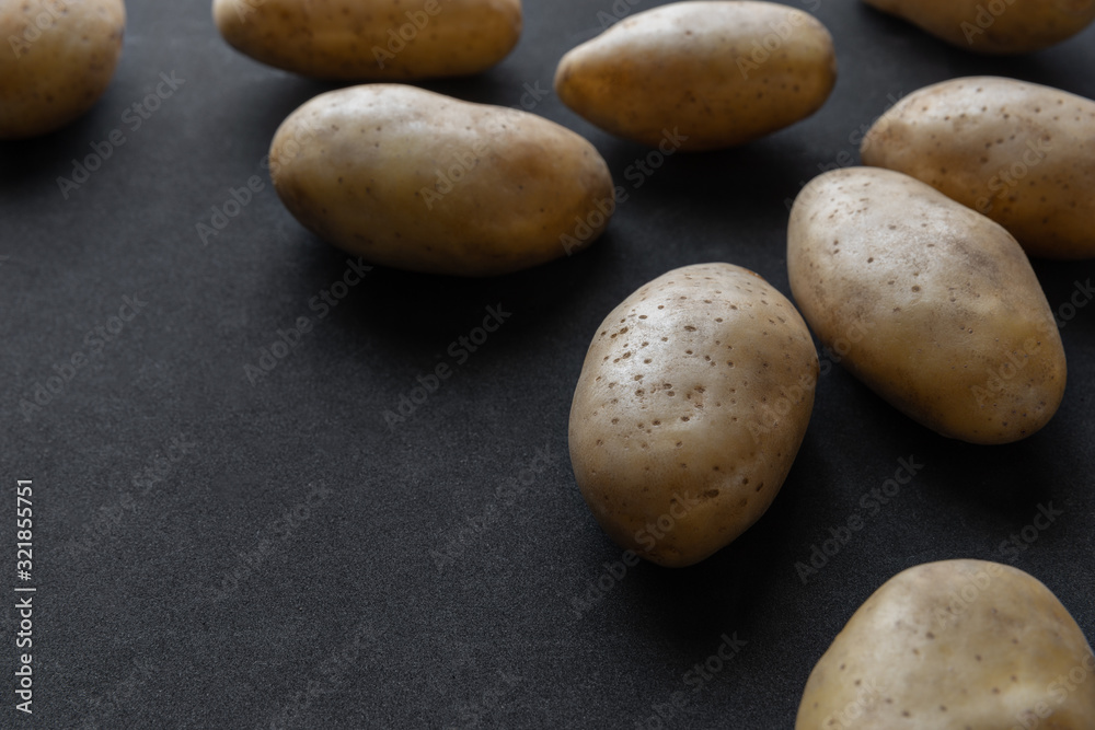 Frame of raw organic potatoes on dark background
