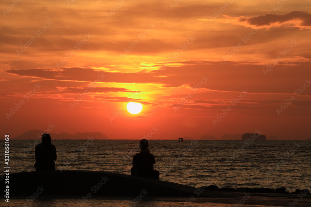 The silhouette of the person watching the sunrise on the beach in the morning The silhouette of the person watching the sunrise on the beach in the morning