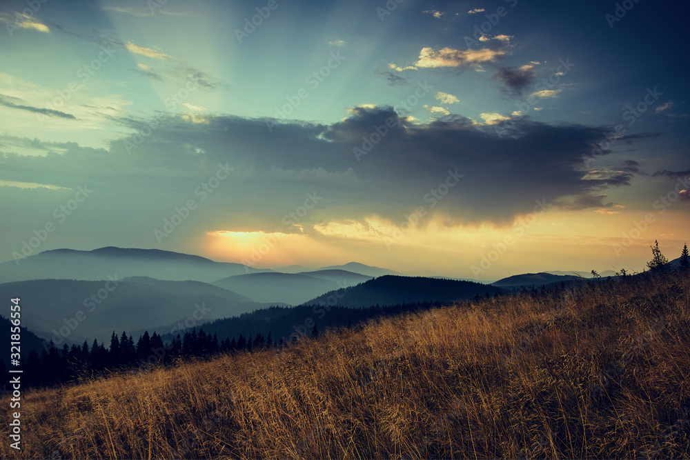 Beautiful landscape in the mountains at sunrise with haze and cloudy sky. View of the magnificent natural scenery of mountains hills. Filtered image: cross processed retro effect. Beautiful landscape in the mountains at sunrise with haze and cloudy sky. View of the magnificent natural scenery of mountains hills. Filtered image: cross processed retro effect.