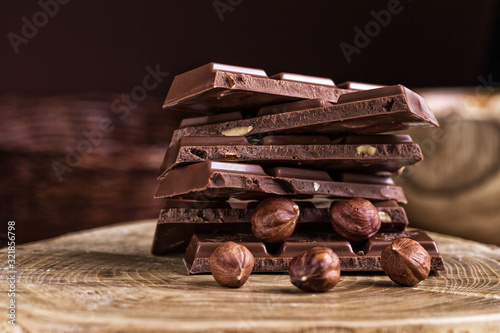 Chocolate bar with hazelnut on a wooden background.