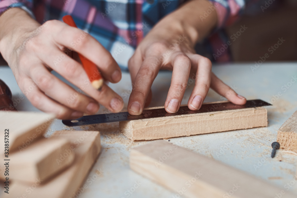 Carpenter hands taking measurement with a pencil of wooden plank. Concept of DIY woodwork and furniture making Carpenter hands taking measurement with a pencil of wooden plank. Concept of DIY woodwork and furniture making