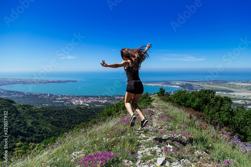 Beautiful, young girl jumps on the slope of a ridge. Late spring (early summer) Gelendzhik.