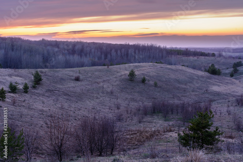 Beautiful spring landscape  sunset  trees  forest  mountains  hills  fields  meadows and sky. Gorgeous  red sky with heavy clouds at sunset. The spring.