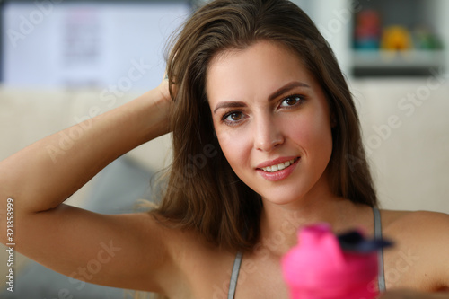 Girl drinks water to maintain perfect figure. Girl is engaged in physical exercises and burns extra calories. Water helps restore body after exercise. Close-up girl straighten hair.