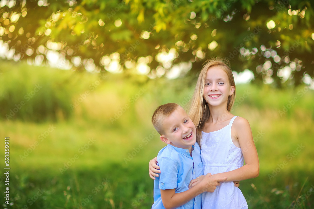 Fototapeta premium Cute children are walking in the evening park. Hug and smile. Children relax and play outdoors. Childhood.