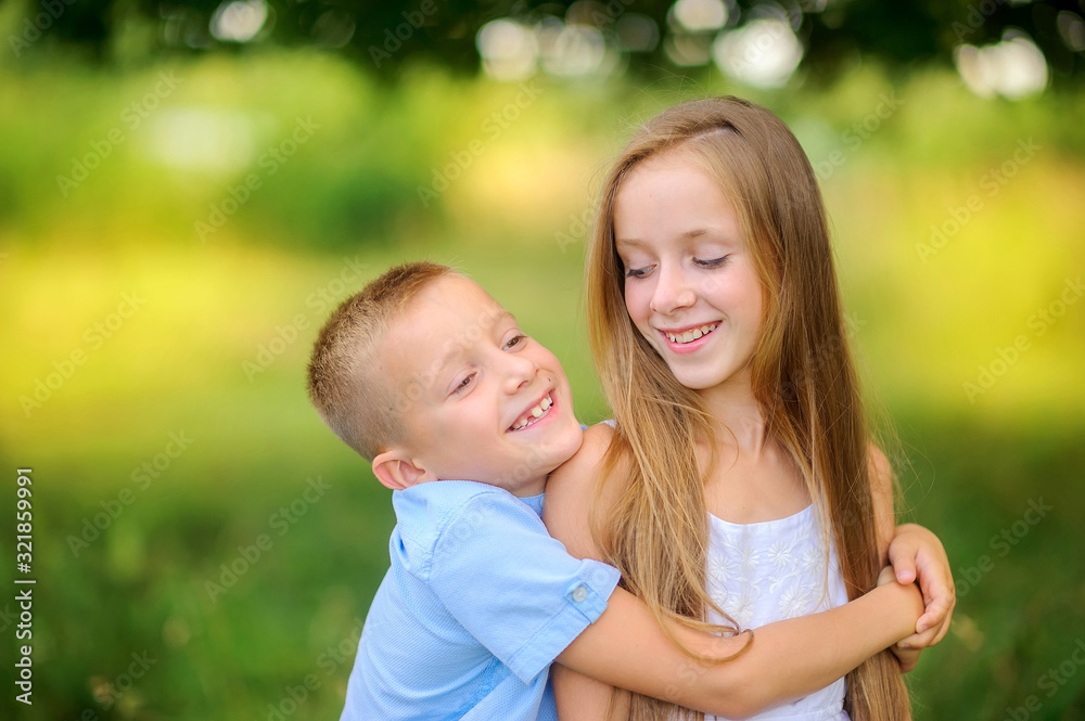 Cute children are walking in the evening park. Hug and smile. Children relax and play outdoors. Childhood. Cute children are walking in the evening park. Hug and smile. Children relax and play outdoors. Childhood.