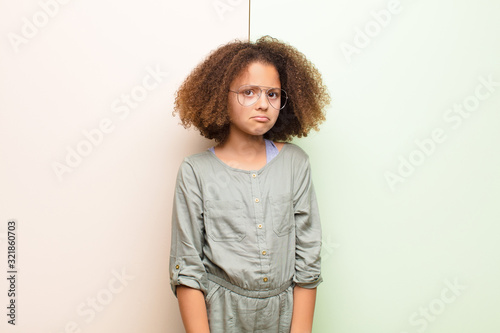 african american little girl feeling sad and whiney with an unhappy look, crying with a negative and frustrated attitude against flat wall photo