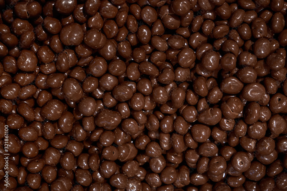 Almonds in chocolate glaze. Nuts in milk chocolate. Brown jelly beans dragee background. Candy shop. Horizontal image. Almonds in chocolate glaze. Nuts in milk chocolate. Brown jelly beans dragee background. Candy shop. Horizontal image.