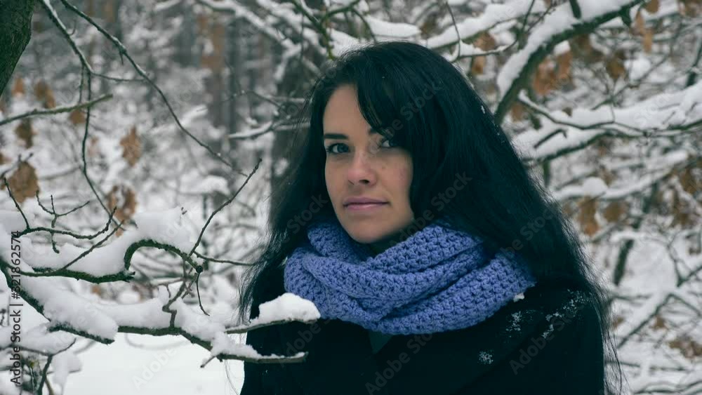 Close-up Beautiful Girl Looking In Camera. Tree Branches Covered With Snow on Background. Frost Weather In the Wood Close-up Beautiful Girl Looking In Camera. Tree Branches Covered With Snow on Background. Frost Weather In the Wood