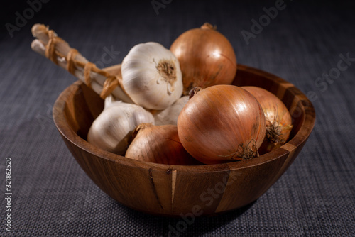 unpeeled onions and garlic in a wooden bowl 